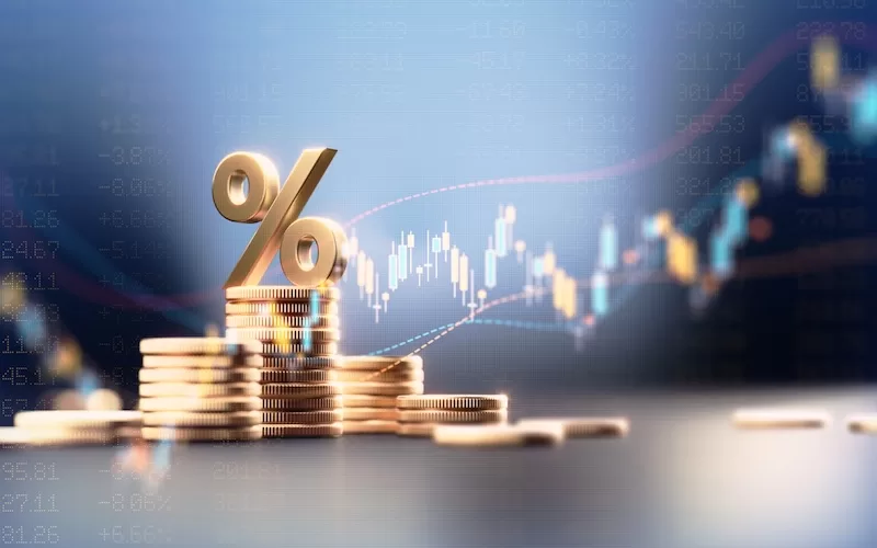 Stacks of gold coins under a percent sign against a rising market chart: the financial footing banking diversification protects
