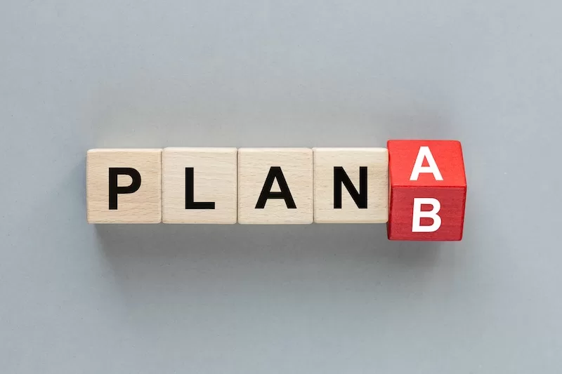 Wooden letter blocks spell PLAN with a red block turning from A to B.
