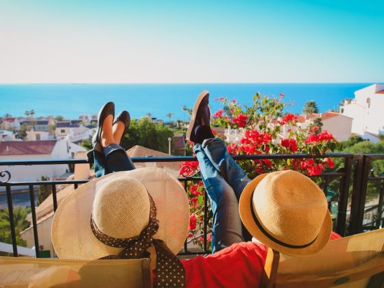 A couple relax on a balcony above whitewashed houses and the sea, the life the Spain non-lucrative visa is built for