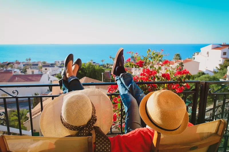 A couple relax on a balcony above whitewashed houses and the sea, the life the Spain non-lucrative visa is built for