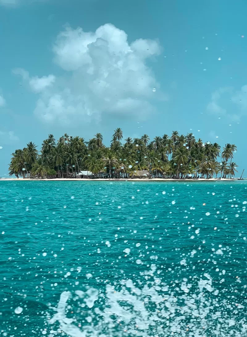 A tiny palm-covered island rises from turquoise water, a postcard in every direction.