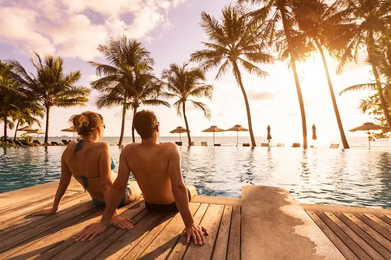 A couple by an infinity pool at sunset, the kind of long-term optionality a second citizenship is bought for.