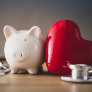 A piggy bank, a red heart and a stethoscope side by side: international asset protection covers wealth and health together.