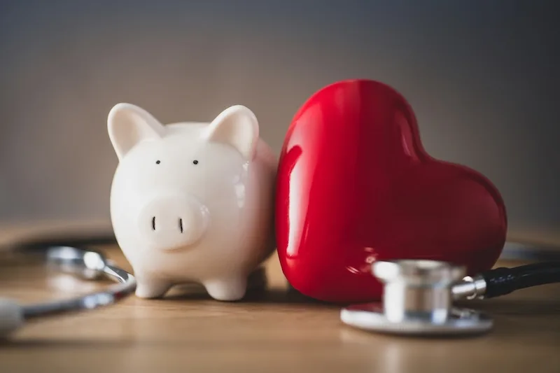 A piggy bank, a red heart and a stethoscope side by side: international asset protection covers wealth and health together.
