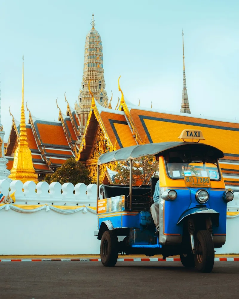 A tuk-tuk passing the Grand Palace in Bangkok, Thailand.