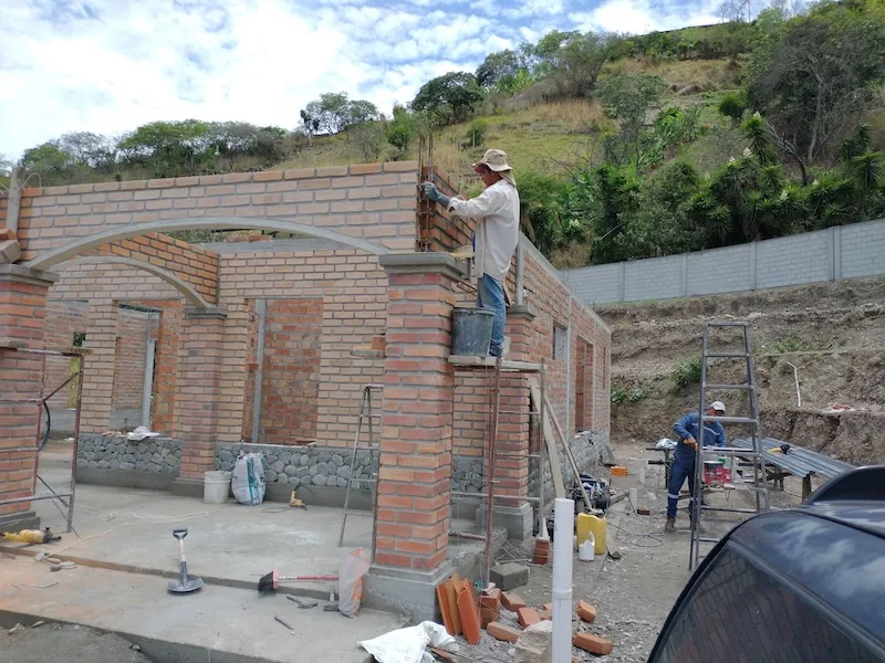 Bricklayers raise the arched brick walls of the house.