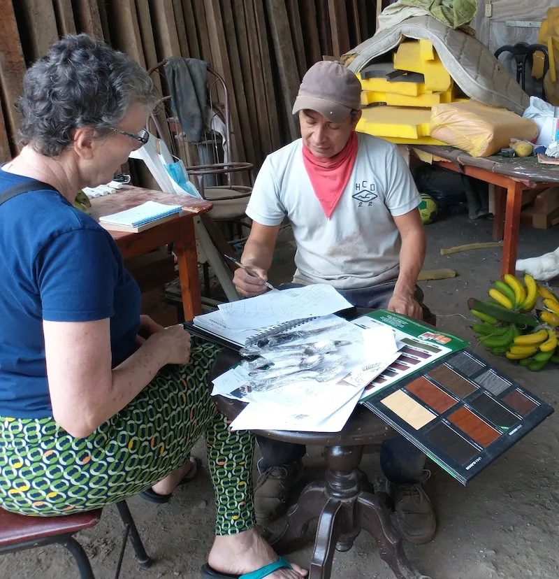 The author and a builder look through plans and color samples at a table.