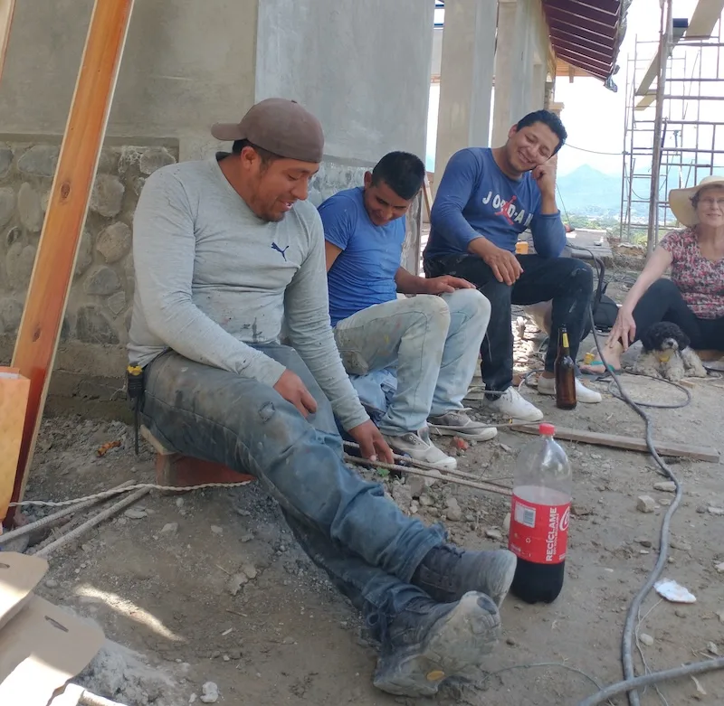 Construction workers take a break on site, with a woman and her dog beside them.