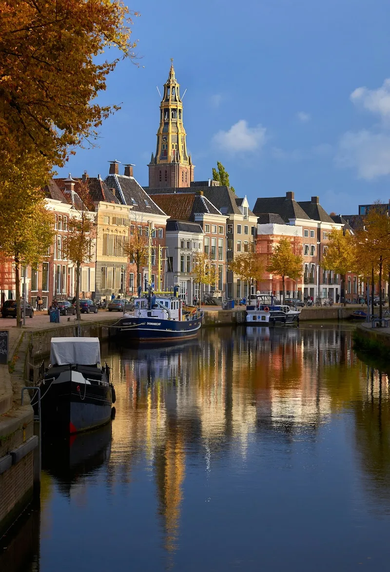 A canal in Groningen, the Netherlands, lined with gabled houses below the tower of the Der Aa-kerk.