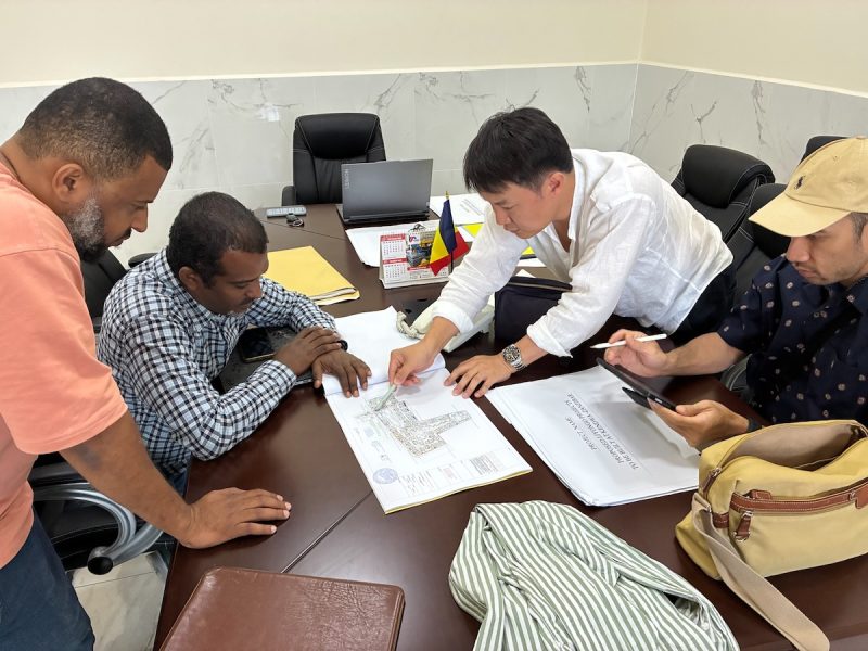 The Liyongo project team, including the lead contractor, architect, landscape architect and electrical engineer, reviewing site plans around a meeting table