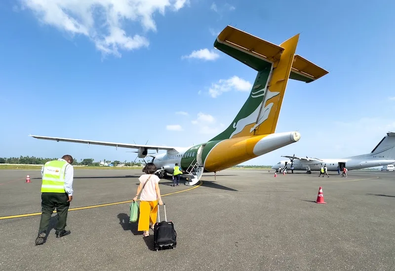 Passengers walk across the apron to board a regional turboprop aircraft.